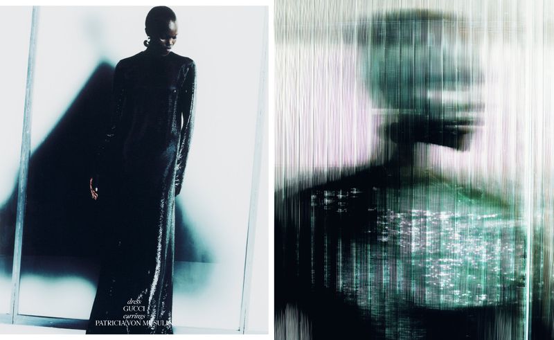Fashion editorial shot of a black woman wearing a black shiny dress and earrings, standing in front of a white wall with shadow.