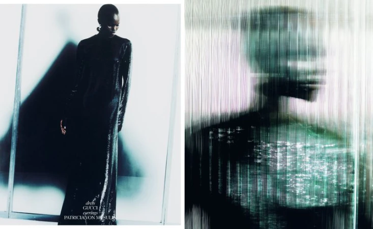 Fashion editorial shot of a black woman wearing a black shiny dress and earrings, standing in front of a white wall with shadow.