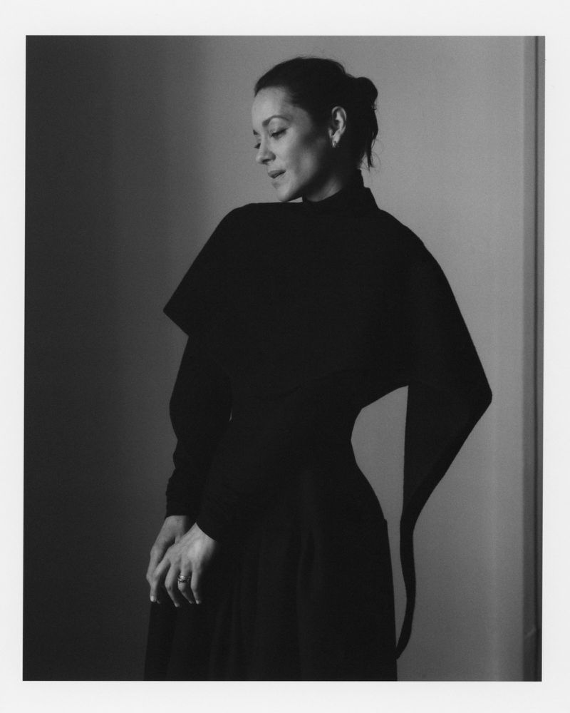 Black-and-white portrait of a woman in a black dress, captured in a photo studio with soft lighting, creating an editorial ambiance.