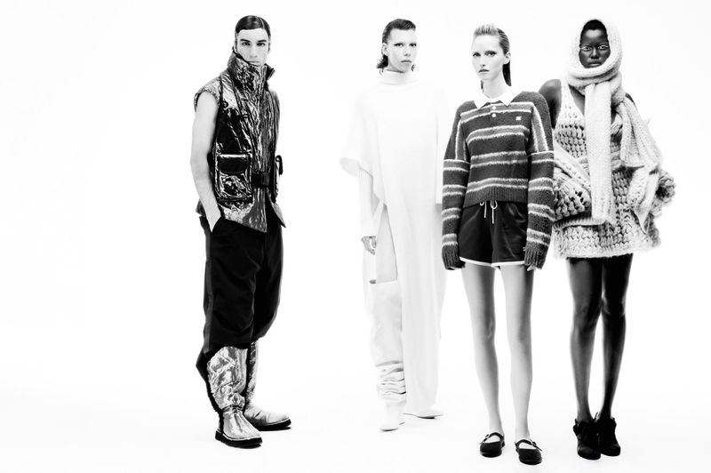 Fashion editorial shot of four adult models wearing futuristic and avant-garde clothing in a bright, minimalist photo studio.