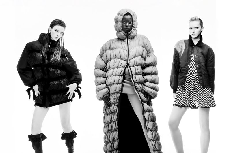 Black and white fashion shot of three models in puffer jackets: one in a knee-length black jacket and two in long puffer coats.