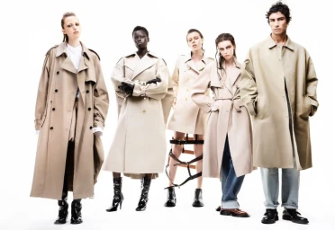 Five fashion models posing in beige and tan trench coats against a bright white seamless background.