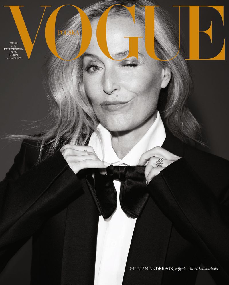 Gillian Anderson winks on Vogue Polska cover, October 2023 issue. She is dressed in a black tuxedo and is adjusting her bow tie.