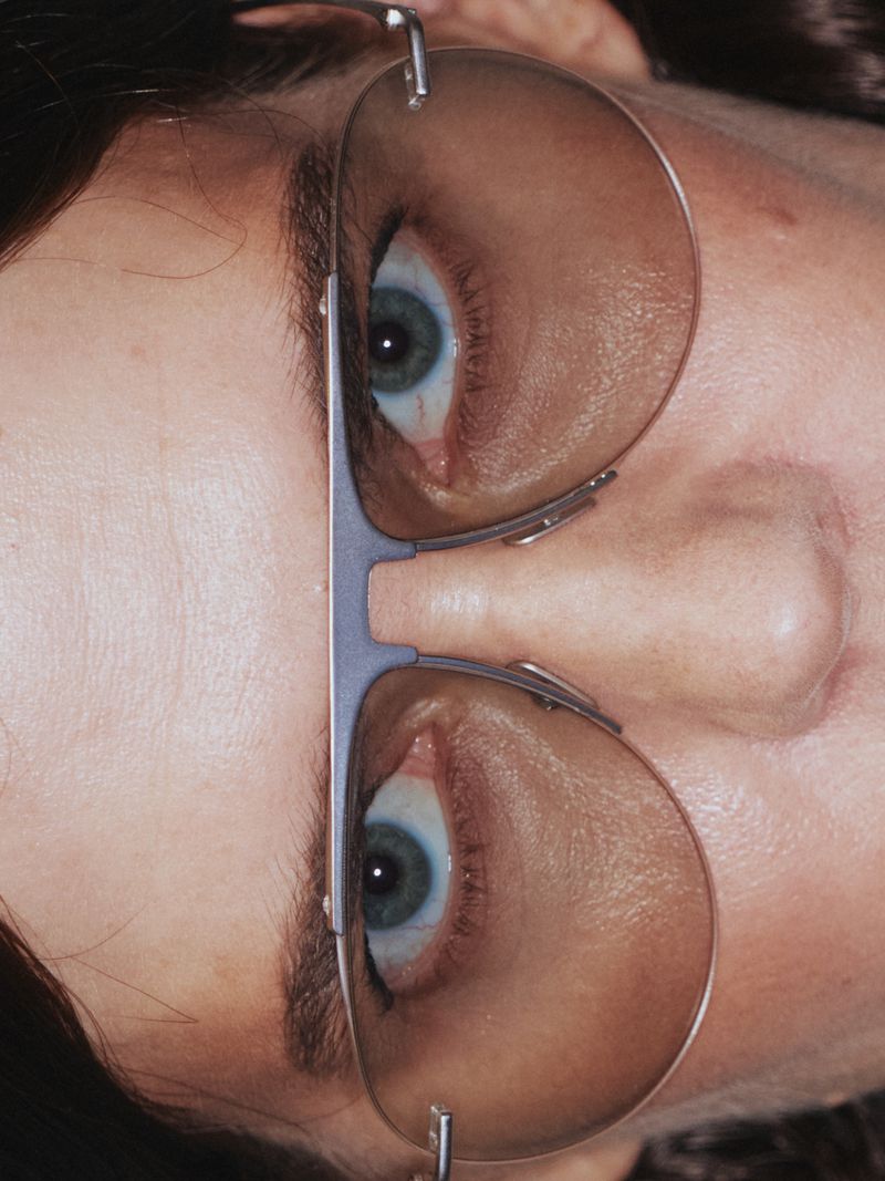 Eye exam with eyeglasses. Close-up of a person's face, wearing metal-framed eyeglasses, and looking upwards in a medical setting.