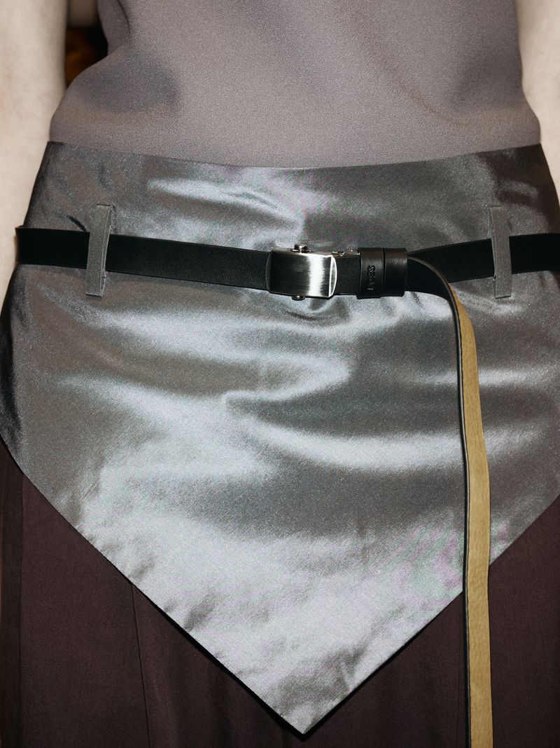 Grey skirt and top with black belt featuring a silver buckle. Tan leather strap hanging down. Fashionable attire on a human torso.
