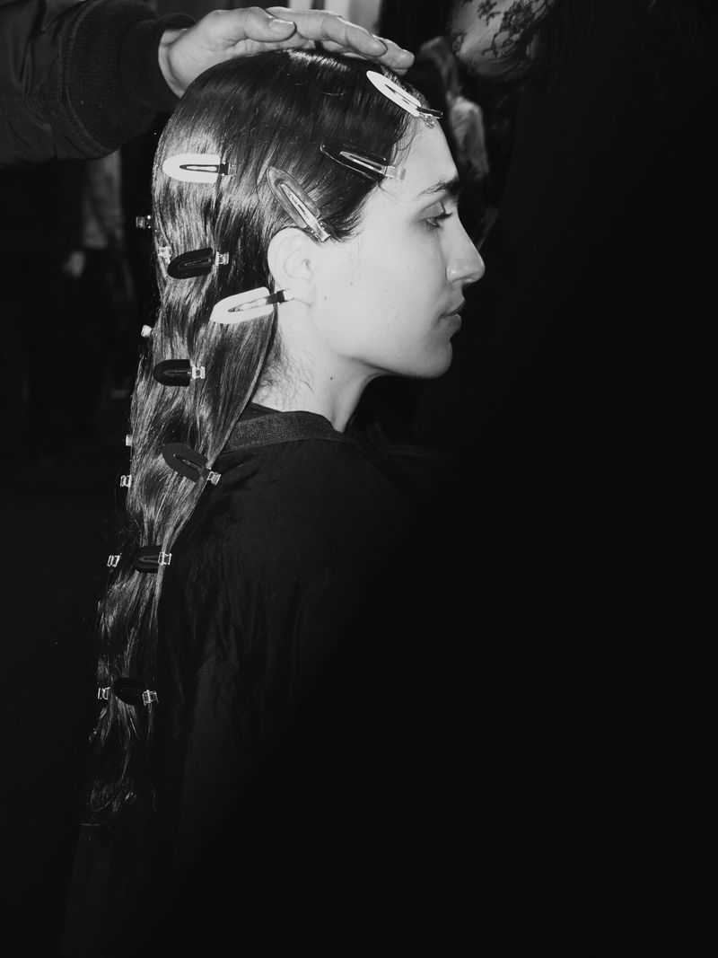 Close-up, monochrome shot of a woman with long wavy hair styled with metal clips, captured in a photo studio setting for hair styling artistry.