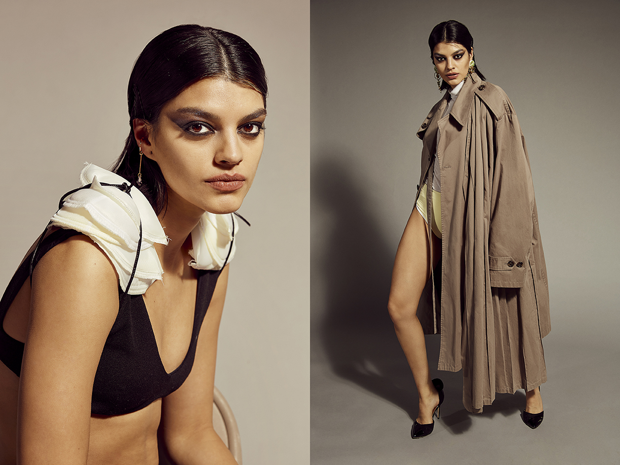 Fashion editorial shot with a woman in black bra with white ruffled collar and trench coat, posing in a studio setting, neutral color palette.