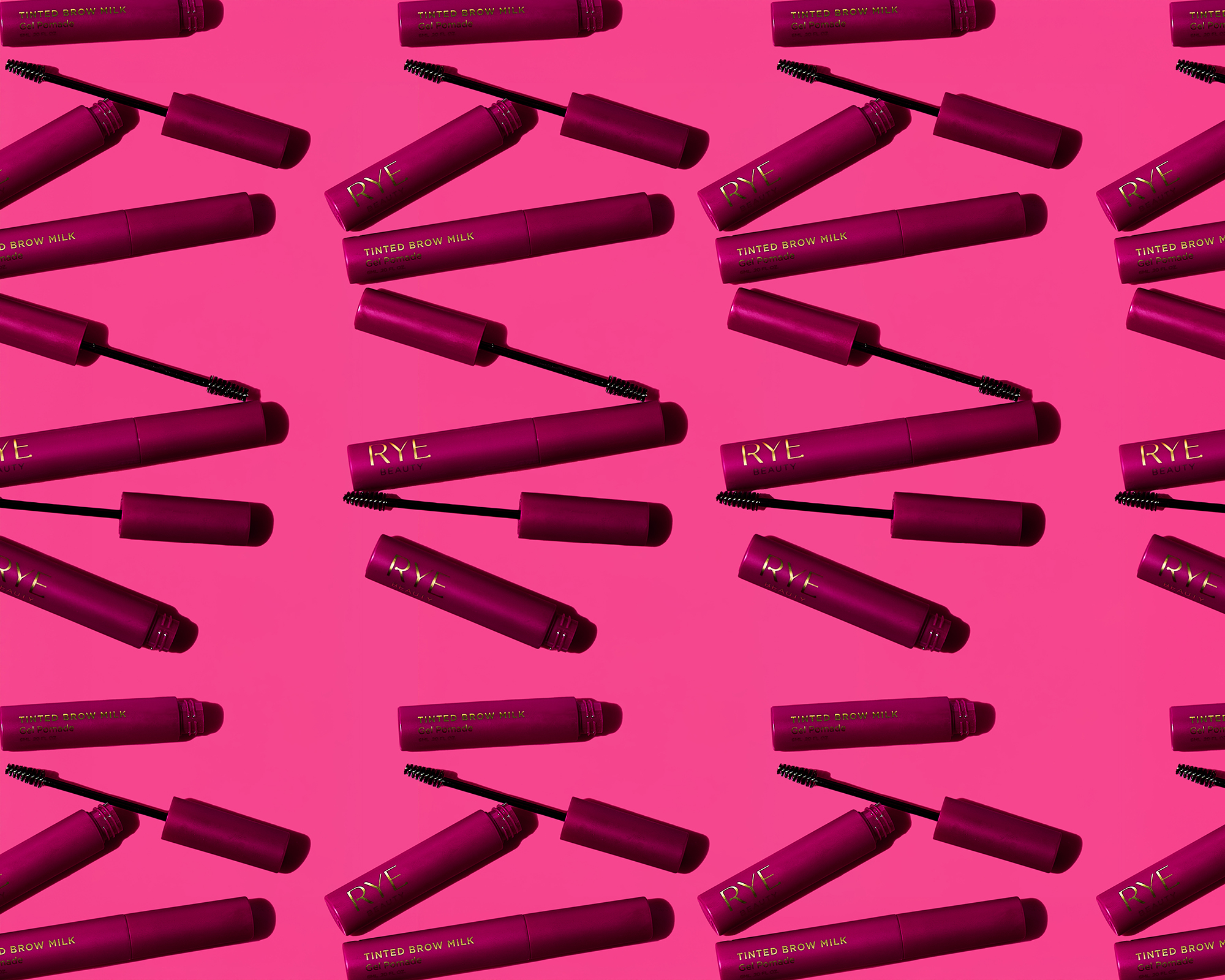 Patterned beauty product background: several plum-colored tubes of 'RYE Tinted Brow Milk' arranged on a bright pink surface. Cosmetic flat lay.