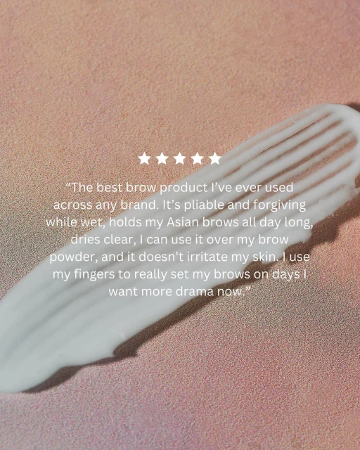 Close-up of a swatch of white cosmetic product, likely for eyebrow grooming, set against a light peach background. Stars included.