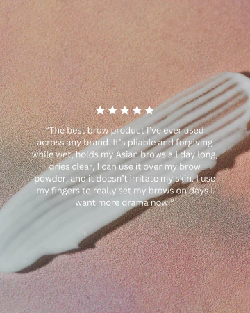 Close-up of a swatch of white cosmetic product, likely for eyebrow grooming, set against a light peach background. Stars included.