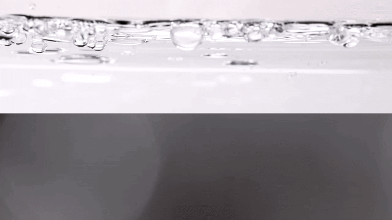 Close-up shot of water with bubbles against a background that transitions from white to dark gray, creating a visually simple and clean composition.