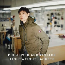 Model wearing an olive green down puffer jacket in a workshop setting with visible sewing tables