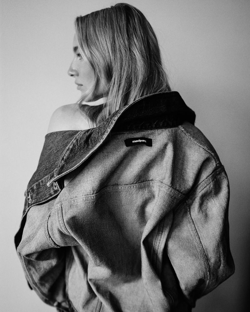 Black and white studio portrait of an adult woman wearing a denim jacket, turned to the side with her shoulders visible.