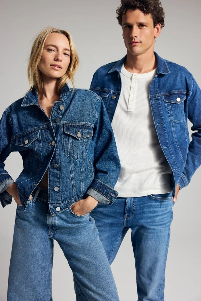 Two models wearing matching blue denim jackets and jeans against a neutral grey studio background for Mavi FW25 campaign.