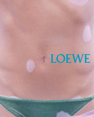 Torso with green bikini bottoms, pink skin with vitiligo, and LOEWE text, showcasing a close-up and details of body positivity in fashion.
