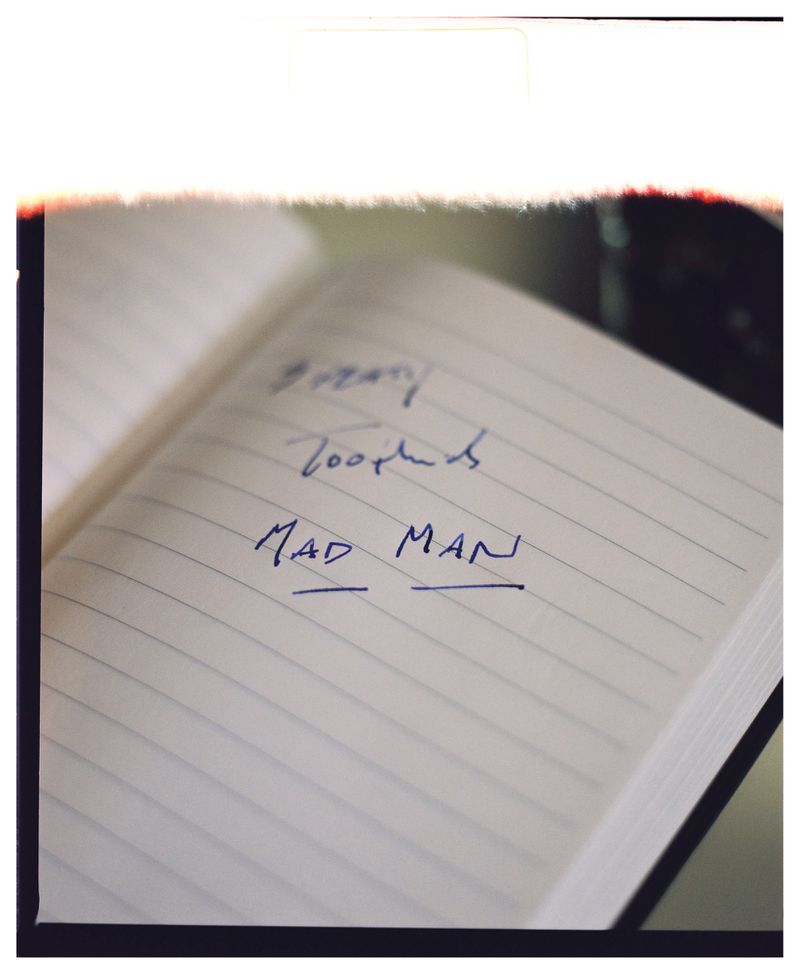 Open notebook with lined pages and handwritten blue ink text, angled close-up shot, providing a glimpse into creative writing process.
