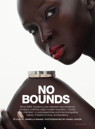 Model Ajok Madel wearing glossy red lipstick posed near Cartier bangles against a white studio background.