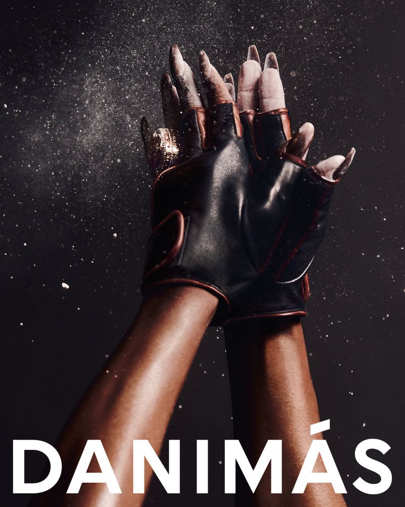 Close-up shot of a pair of gloved hands, palms facing inward, fingertips dusted with white powder against a dark backdrop.