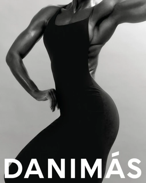 Monochrome portrait of a muscular woman in a black form-fitting dress against a solid background, highlighting strength and fashion.