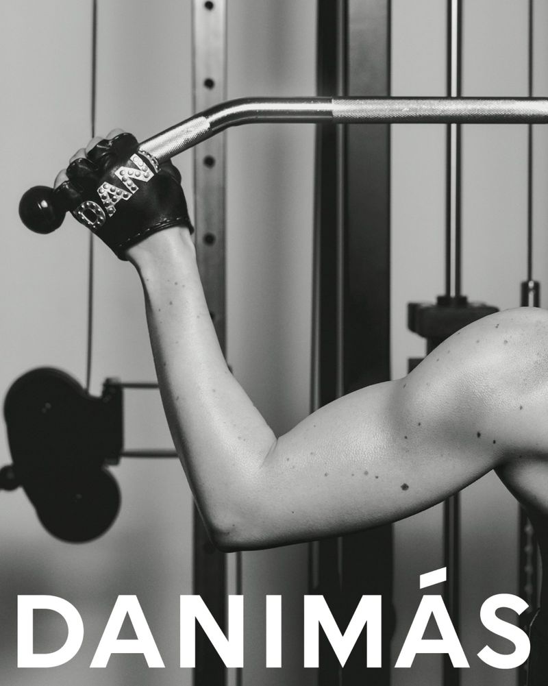 Monochrome shot of a muscular arm pulling down on a lat pulldown machine in a fitness studio. Focus on strength and workout.