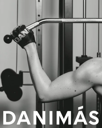 Monochrome shot of a muscular arm pulling down on a lat pulldown machine in a fitness studio. Focus on strength and workout.