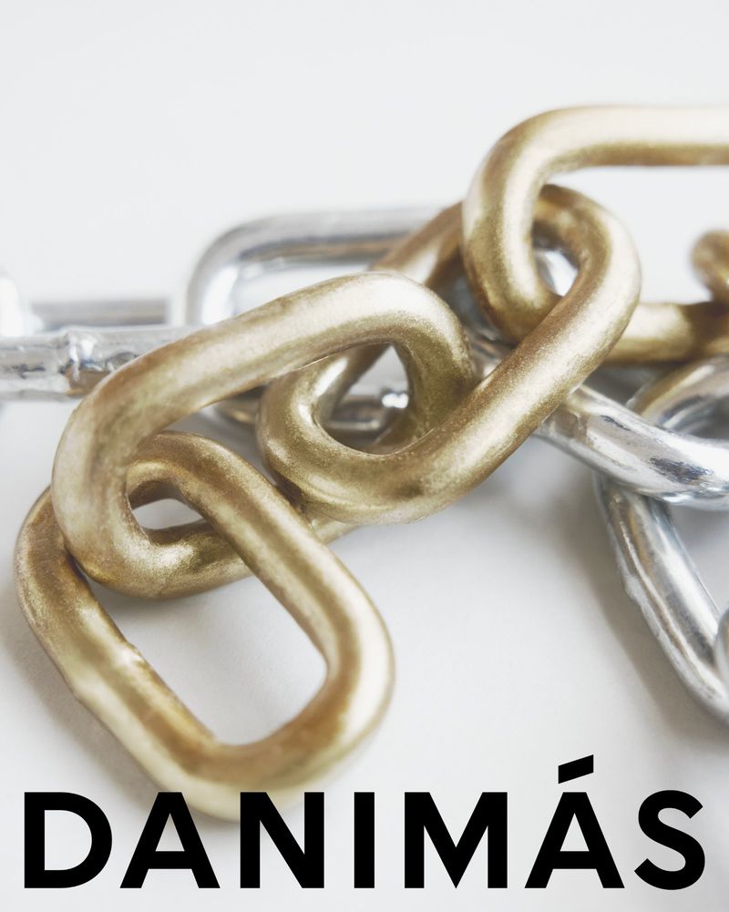 Close-up of interlocked gold and silver metal chains on a clean white surface, emphasizing their texture and connection.