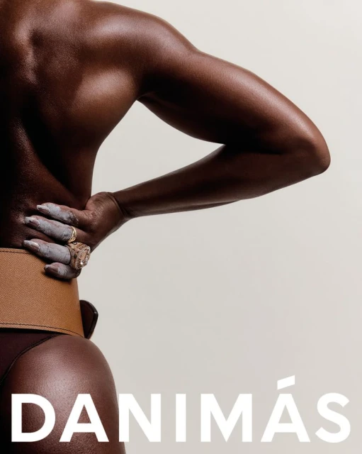 Back view of dark-skinned model wearing a brown belt and dark bottoms, posing against an off-white background with "DANIMÁS" text.