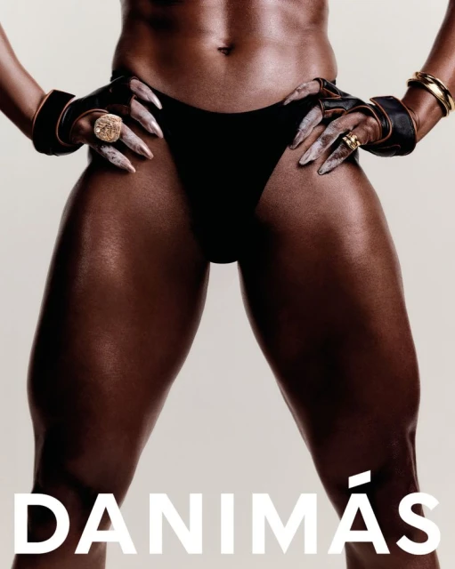 Close-up studio shot of an adult female with dark skin wearing a black swimsuit bottom and gold jewellery. Muscular thighs are in focus.
