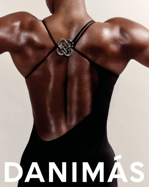 An adult woman's back is captured in a close-up studio shot, showcasing her bare skin, dress straps, and a decorative metal piece.