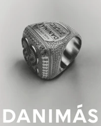 Monochrome product shot of a large embellished championship ring featuring encrusted stones and stamped text against a plain background