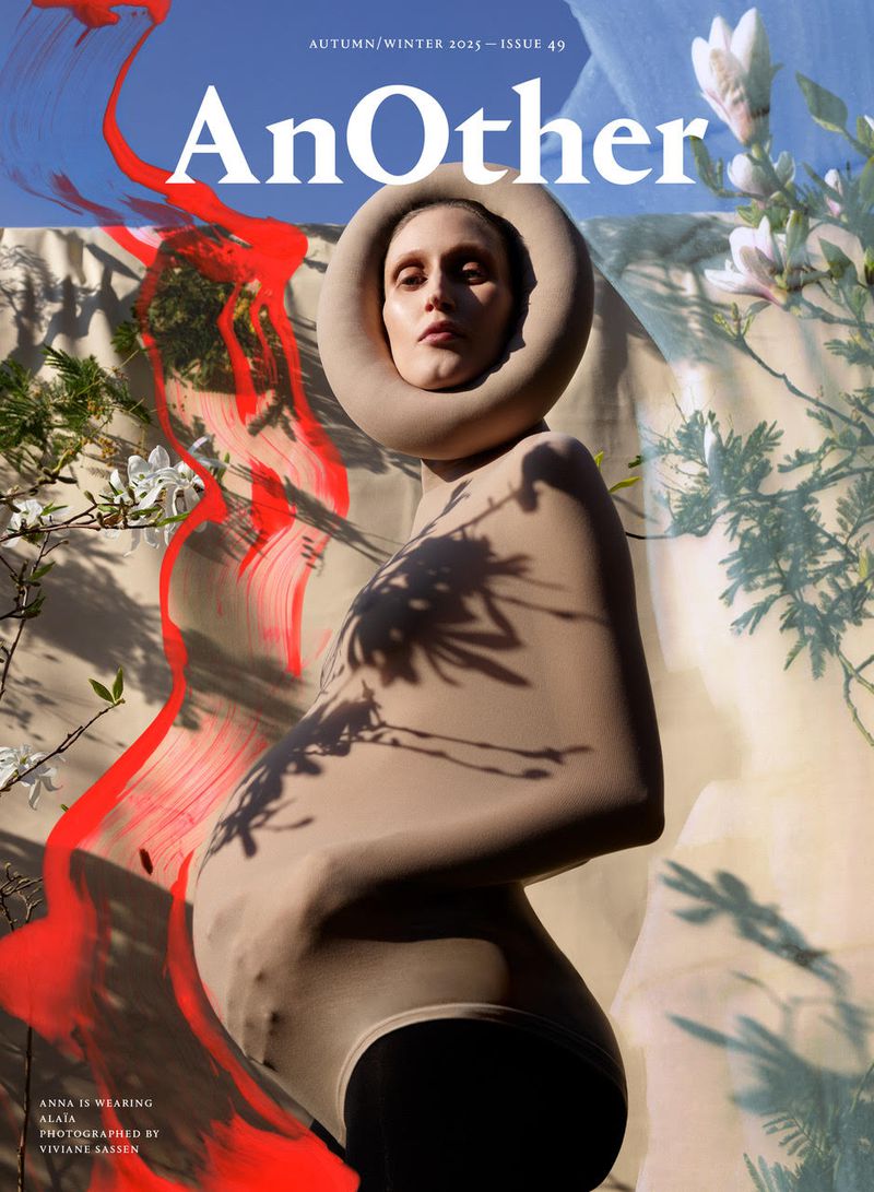 Fashion magazine cover features a person wearing a nude-toned body suit, statement neck piece, and minimal makeup in an outdoor setting.