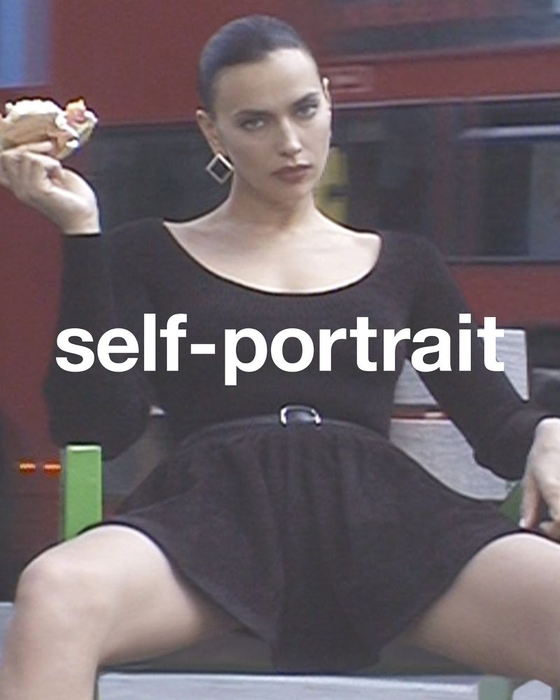 Adult female sitting, holding food, wearing a black long-sleeve dress and square earrings in front of a blurred red vehicle.