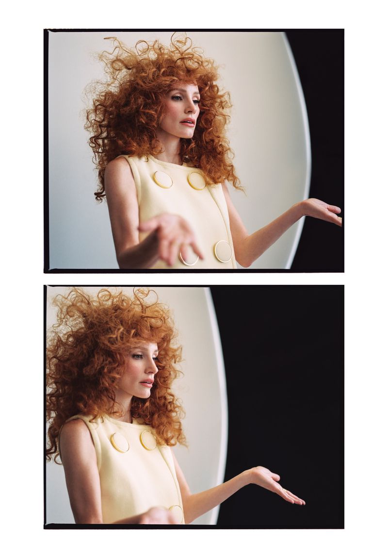 Red-haired woman in a sleeveless, yellow dress with a high neckline, striking a pose with outstretched hands in a photo studio setting.