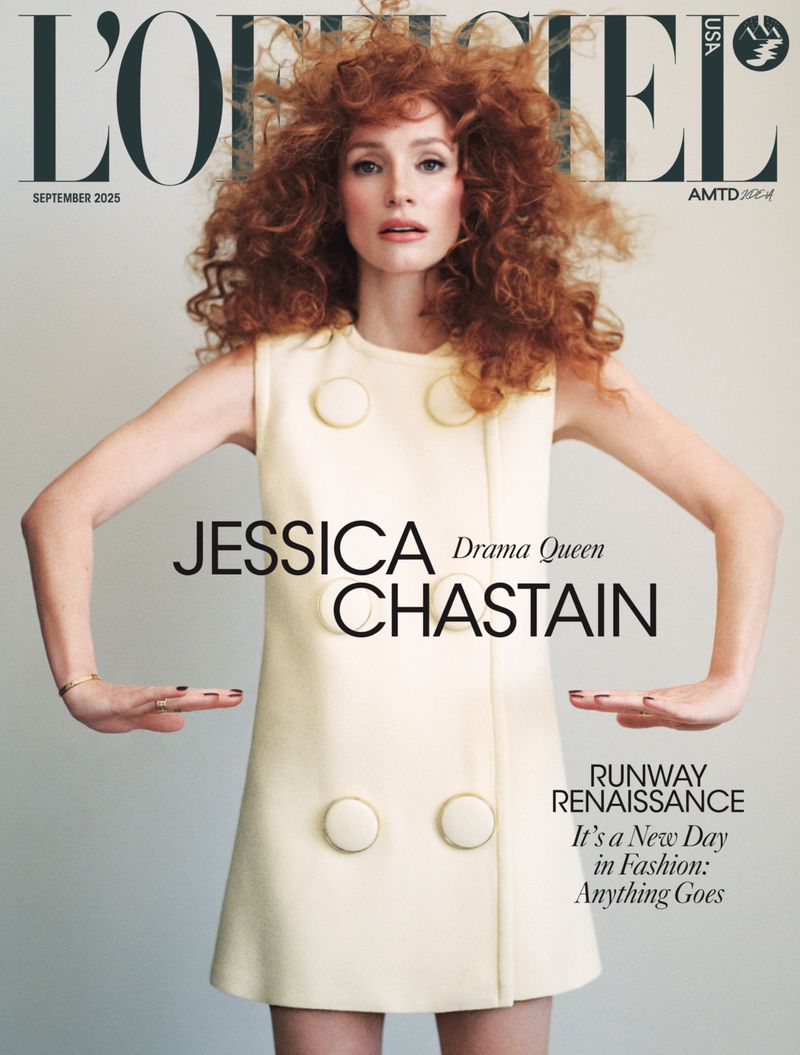 Magazine cover featuring Jessica Chastain with red curly hair, wearing a cream-colored dress with large buttons, arms outstretched, fashion portrait.