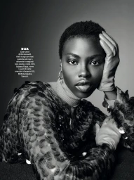 Black woman wearing a textured sequined top and leather gloves with her hand to her face in a monochrome portrait.