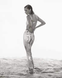 Elsa Hosk wearing a shimmering sequin dress standing on a sandy beach for Elle Australia by photographer Justin Woo.