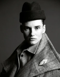Black and white portrait of Giedre Dukauskaite wearing a wool pinstripe coat, felt hat, and crystal brooch for Harper's Bazaar España.