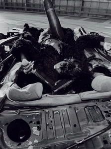 Model Anok Yai lying across the back of a dismantled car in a black and white editorial photograph for The Perfect Magazine.