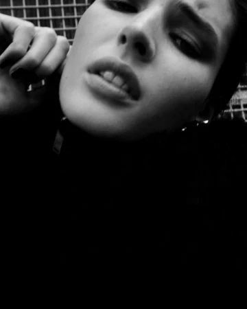 Close-up black and white portrait of a young adult woman with dark hair and light skin tone looking upward with a serious expression.