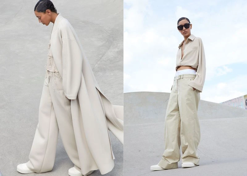 Two fashion models pose in tan clothing. One model wears a long tan coat and the other wears a tan button-down shirt and pants.