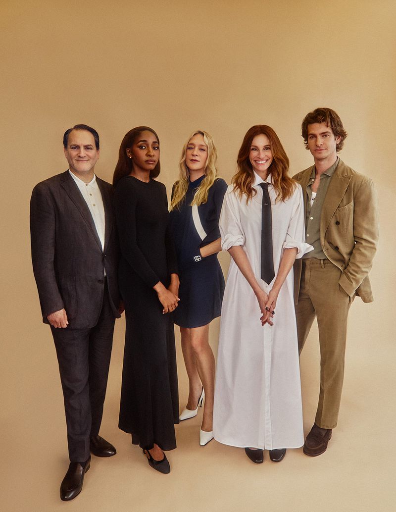 Group portrait of five people standing together indoors. The group includes adult men and women, each with a neutral facial expression.