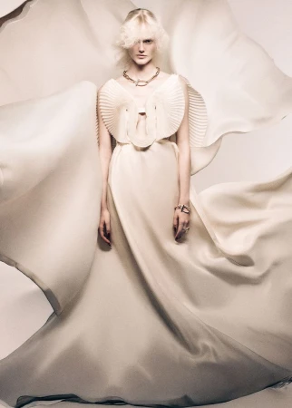 Model Lily Chapman wearing an avant-garde cream pleated gown with billowing fabric for a Grazia International studio shoot.