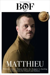 Portrait of Matthieu Blazy wearing a brown collared shirt against a black background for The Business of Fashion BoF 500.