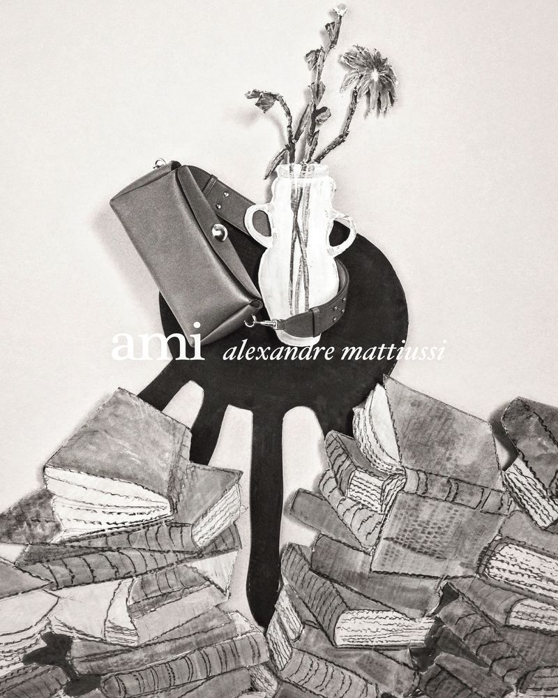 Still life image with a bag, books, and flowers in a vase, set against a neutral backdrop, conveying a sense of academic fashion and style.