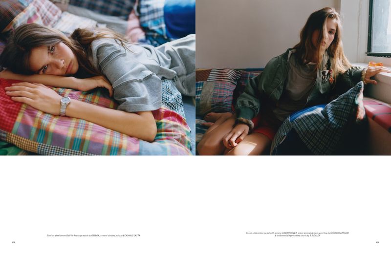Indoor fashion shot featuring a young woman in casual clothing lying on a colorful patchwork quilt, next to a second young woman.