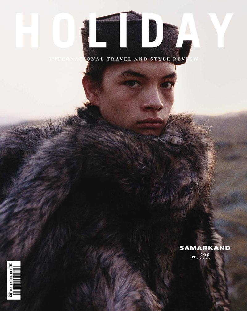 Magazine cover featuring a person in a fur coat and hat against a blurred outdoor background, promoting international travel and style.