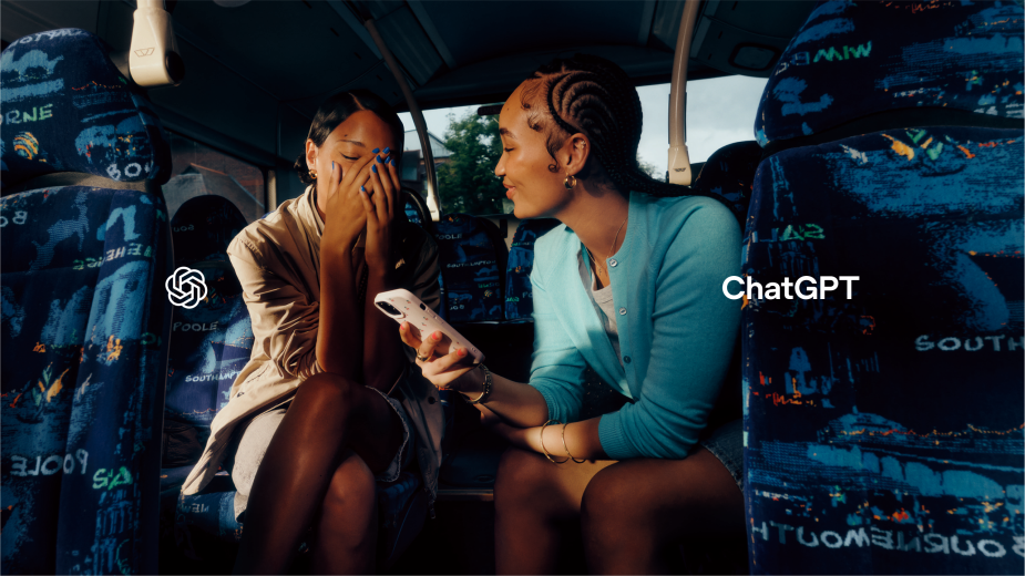 Two young women are sitting on a bus; one looks at a phone while the other covers her face. Soft lighting and cool color grading.