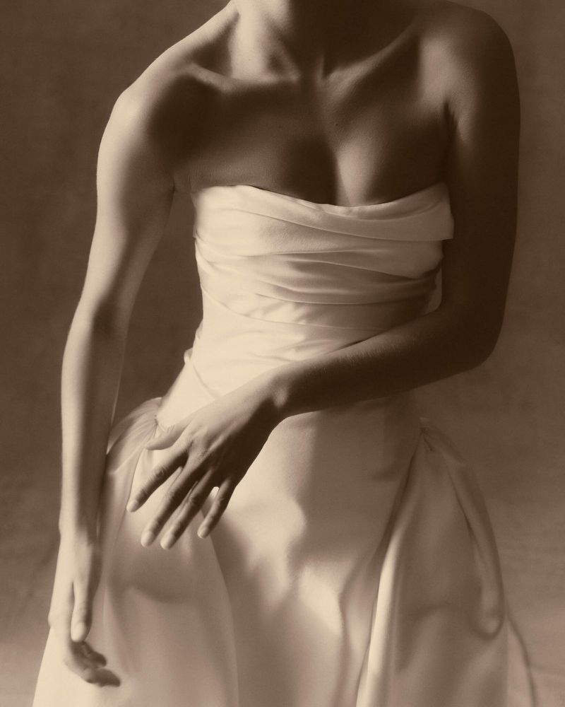 Elegant studio portrait of a woman in a draped dress, showcasing neutral colors, soft lighting, and fine art photography technique.