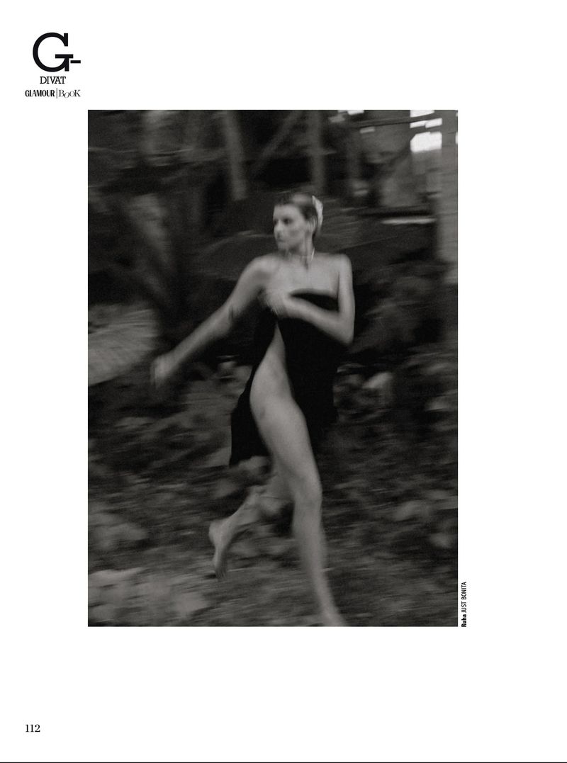 Black and white fashion shot of a woman partially draped in fabric, running barefoot in a blurry outdoor environment.