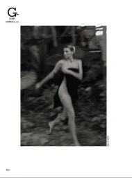 Black and white editorial fashion image of a woman wrapped in dark fabric running outdoors through a blurred natural landscape.